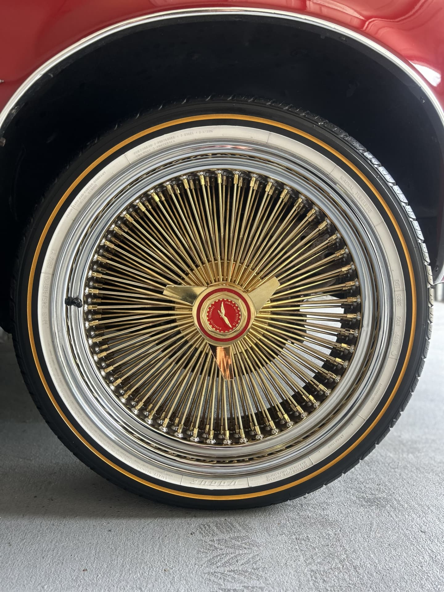 Polished gold wire-spoke wheel and whitewall tire on a red 1979 Pontiac Firebird after a wheel detail in Kenner, Louisiana
