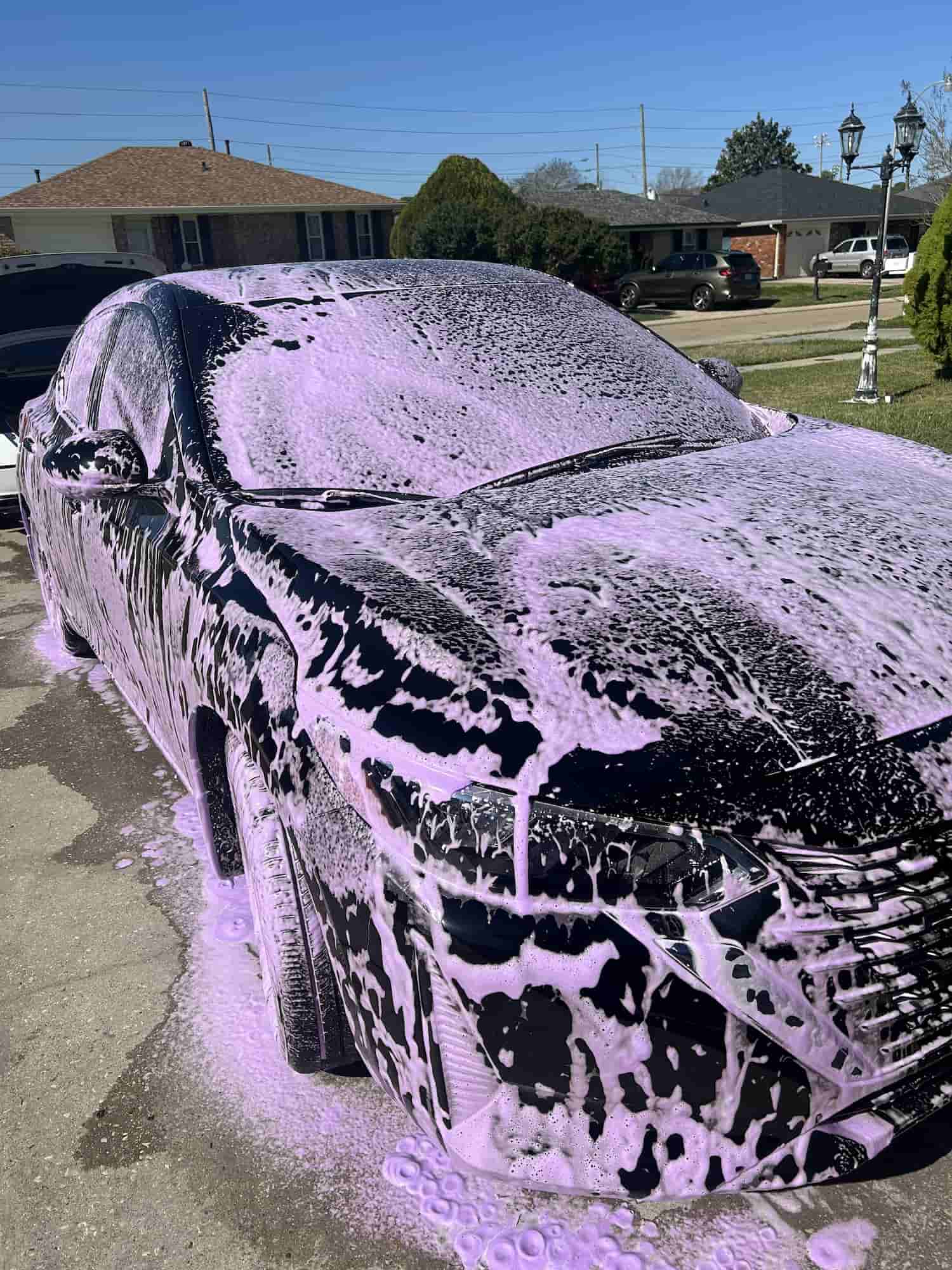 Black Nissan Sentra under thick purple foam during a safe hand wash mobile detail in Kenner, Louisiana
