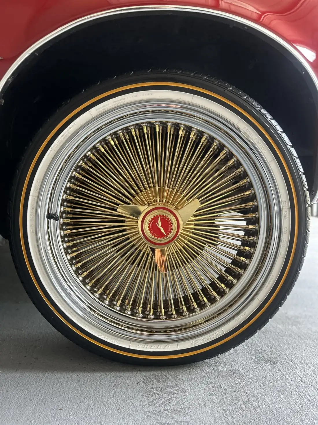 Polished gold wire-spoke wheel and whitewall tire on a red 1979 Pontiac Firebird after a wheel detail in Kenner, Louisiana